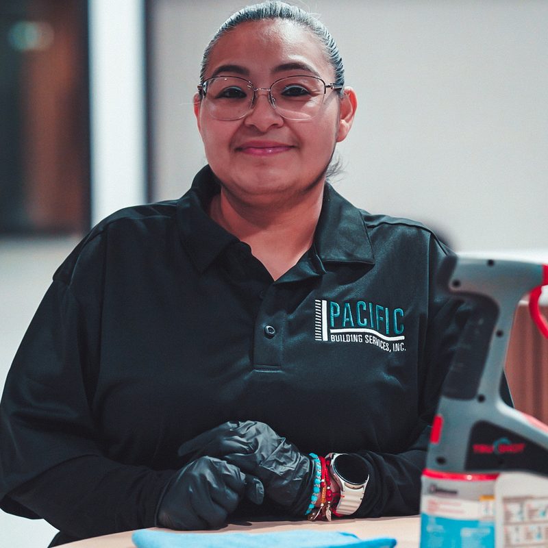 Smiling PBS crew member in glasses and gloves, wearing a black PBS polo.