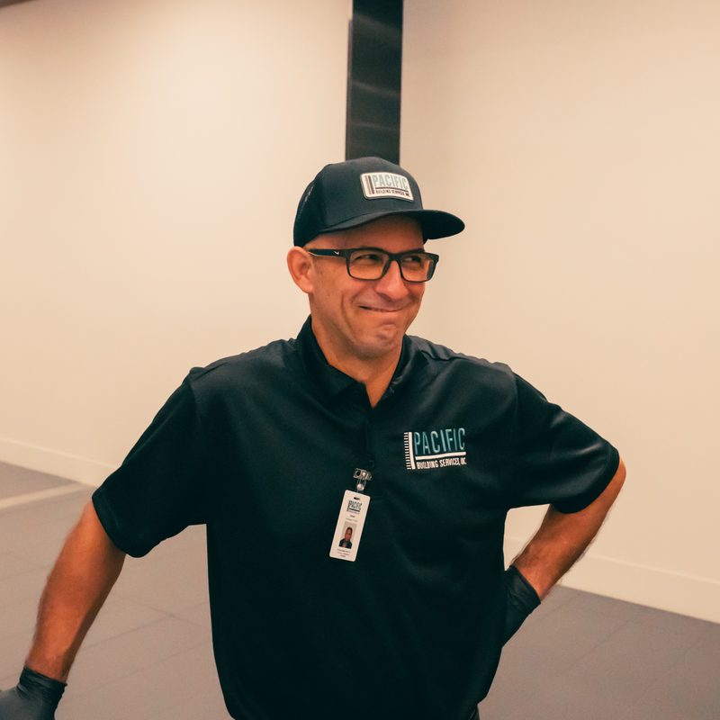 PBS crew member in a black cap and glasses, smiling with one hand on his hip.